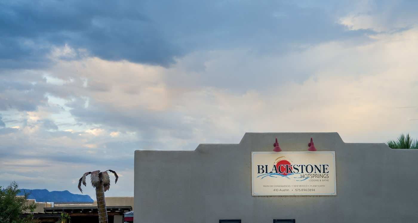 The parapet and palm tree above Blackstone Hotsprings against a clear sky